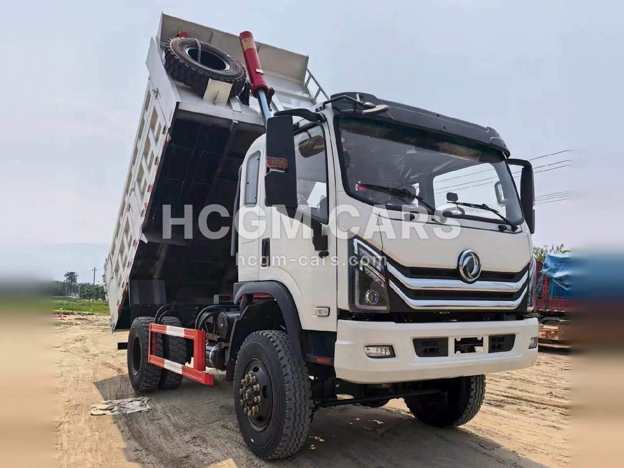 White Dongfeng 4x4 off-road dump truck with the body raised, front three-quarter view